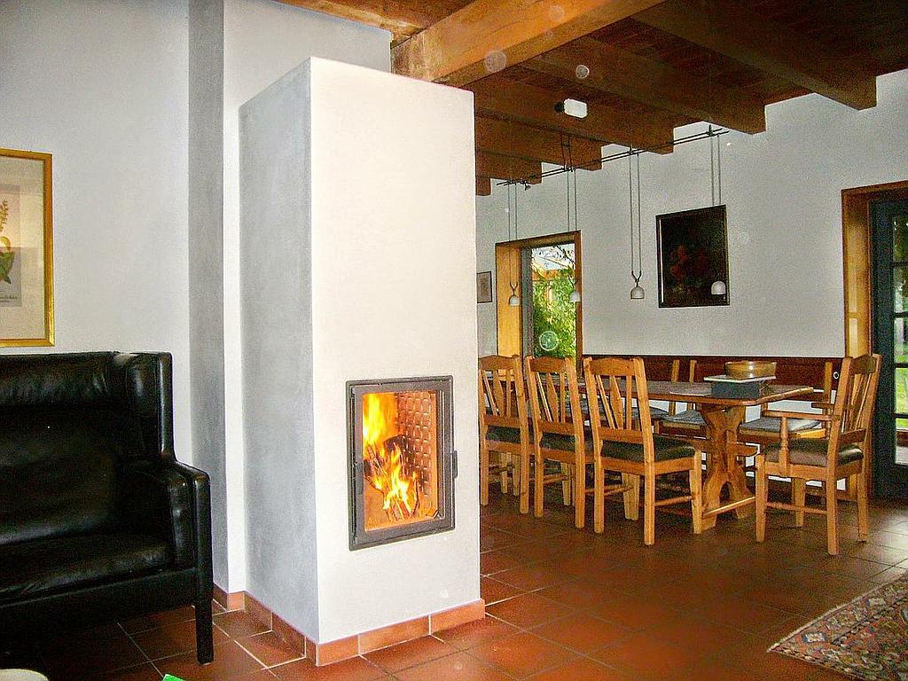 Kompakter Speicherofen in traditionellem Wohn-Essbereich mit Terrakottafliesen und Holzbalkendecke