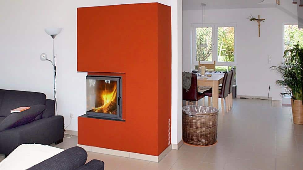Moderner Kamin mit orangefarbener Verkleidung in offenem Wohn-Essbereich mit hellen Fliesen und dunklem Sofa