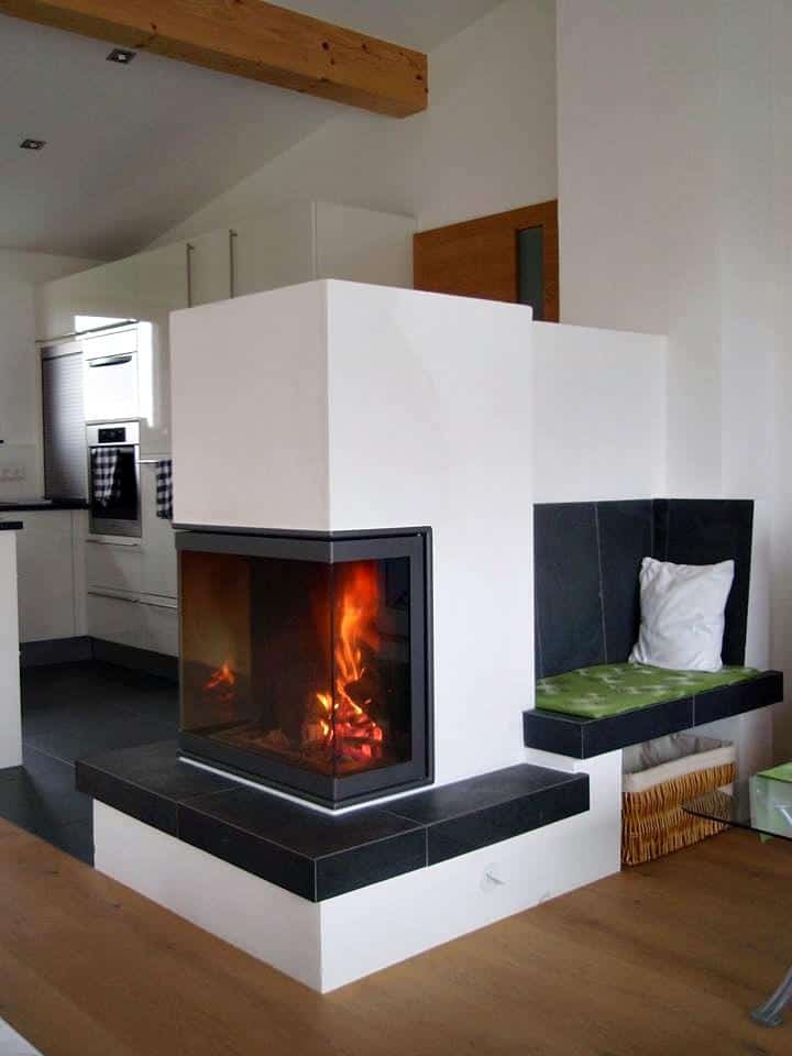 Eckkamin mit großer Sichtscheibe und integrierter Sitzbank in modernem Wohnbereich mit offener Küche