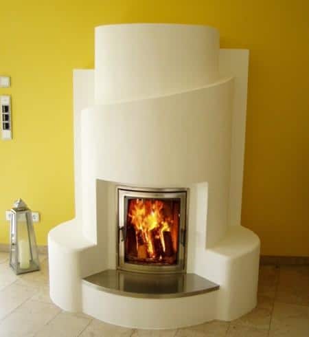 Designkamin mit geschwungener Putzform und Edelstahlfeuerraum in modernem Wohnraum mit gelber Wand