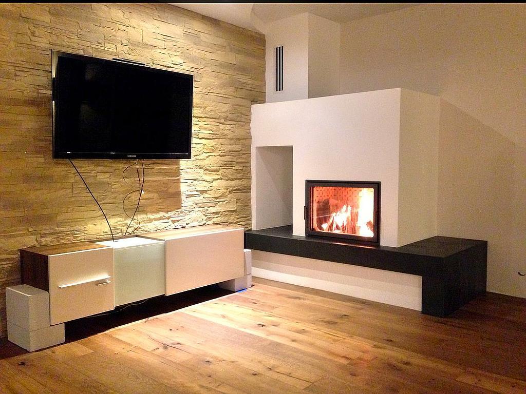 Moderner Kamin mit breiter Sitzbank und Natursteinwand in Wohnzimmer mit TV und Parkettboden