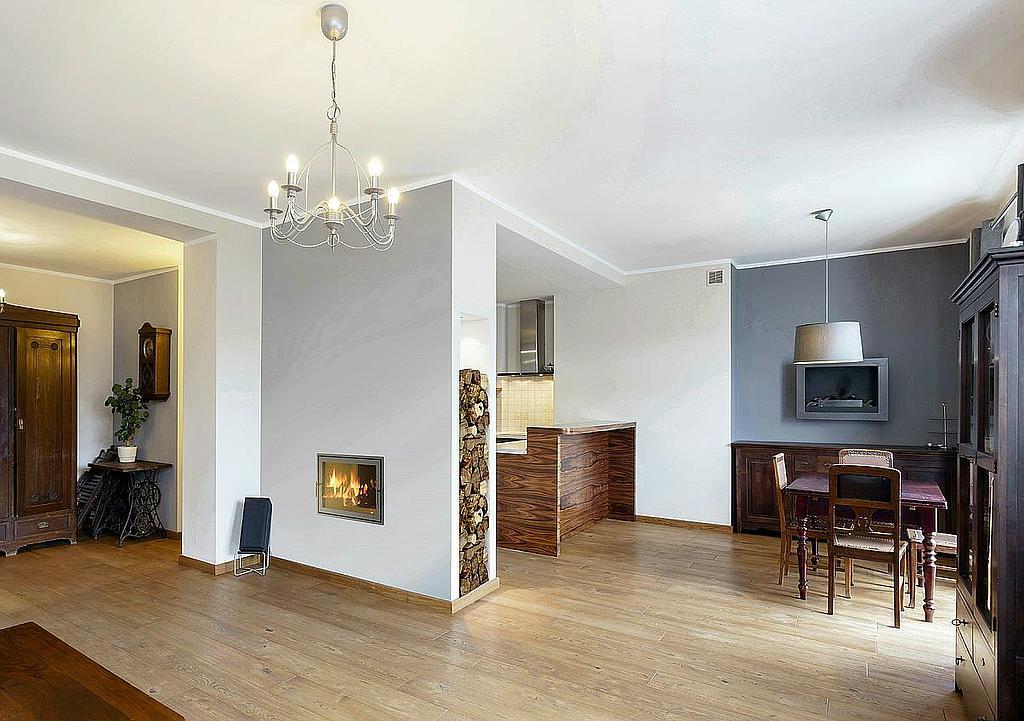 Moderner Kamin mit integriertem Holzfach in offenem Wohn-Essbereich mit klassischen Möbeln