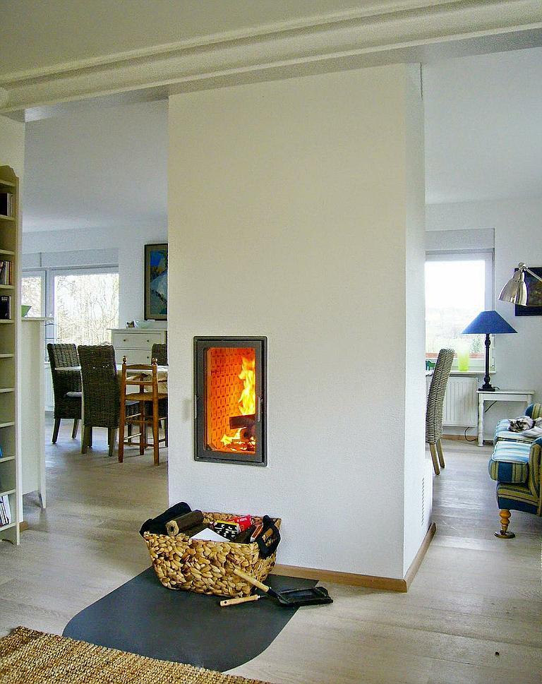 Moderner schmaler Kamin in heller Wohnküche mit Korb für Kaminzubehör auf Parkettboden