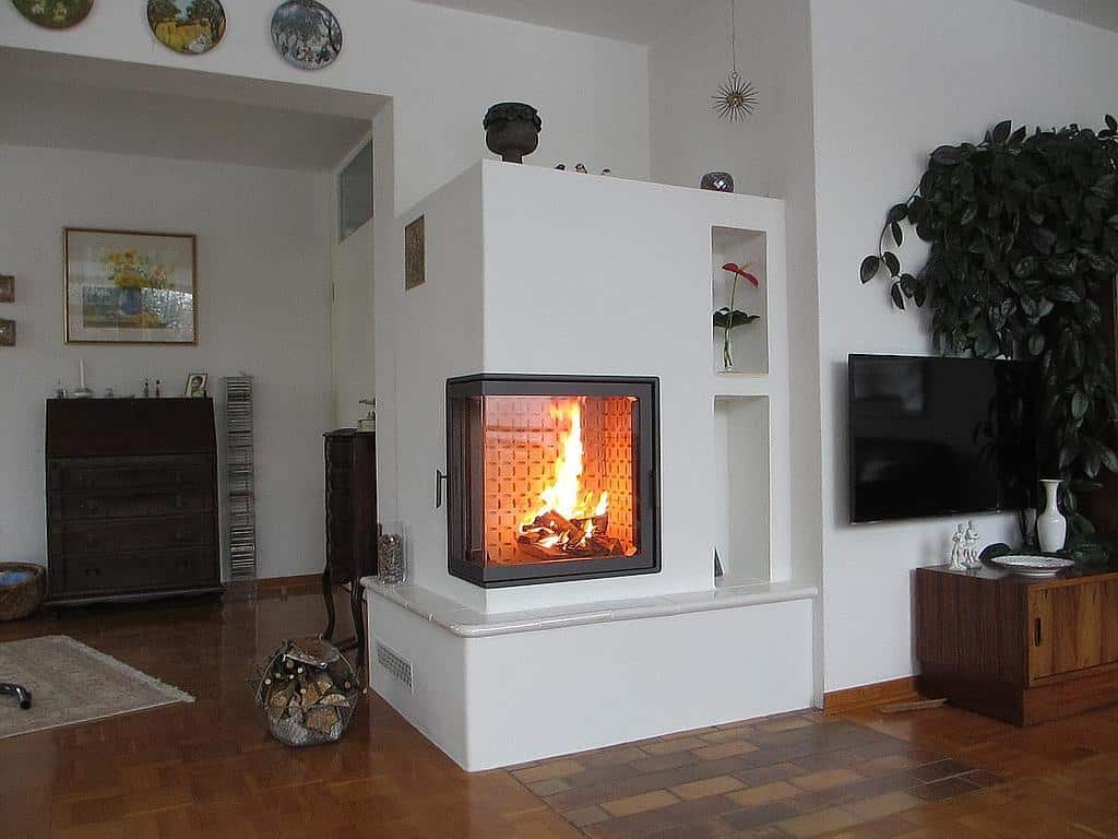 Klassischer Speicherofen mit Eckverglasung in liebevoll eingerichtetem Wohnzimmer