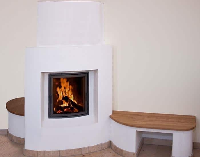 Traditioneller Kachelofen mit weißem Putz und Holzsitzbank