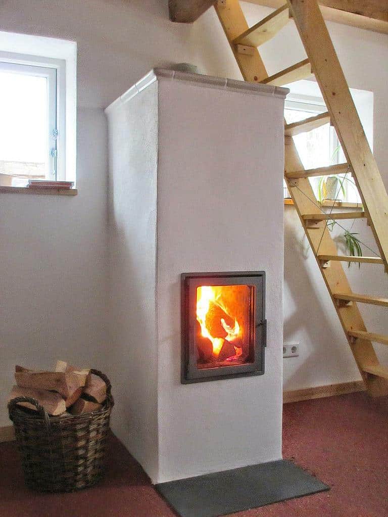 Kompakter Speicherofen in schlichtem Design mit Holzleiter im Hintergrund