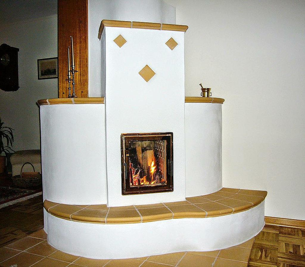 Traditioneller Speicherofen mit abgerundeter Sitzbank und keramischer Bordüre