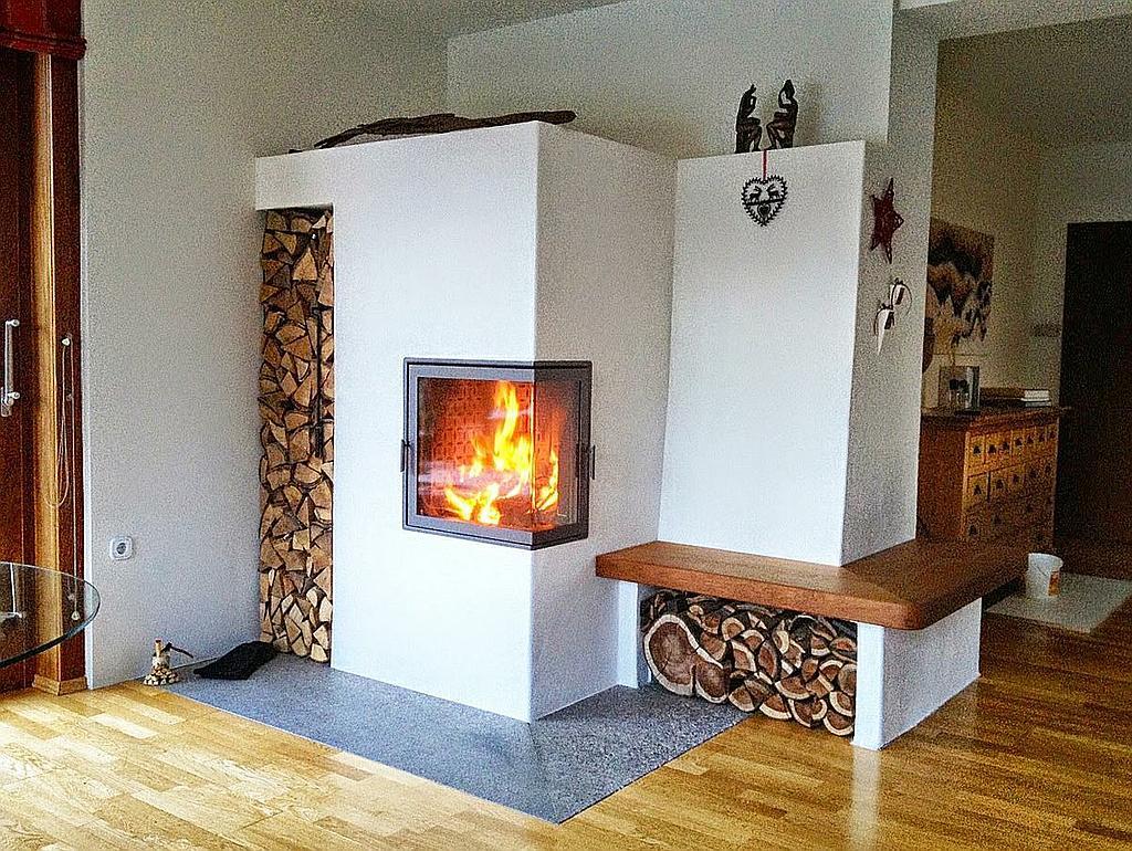 Traditioneller Speicherkamin mit Holzlager und integrierter Sitzbank aus Holz