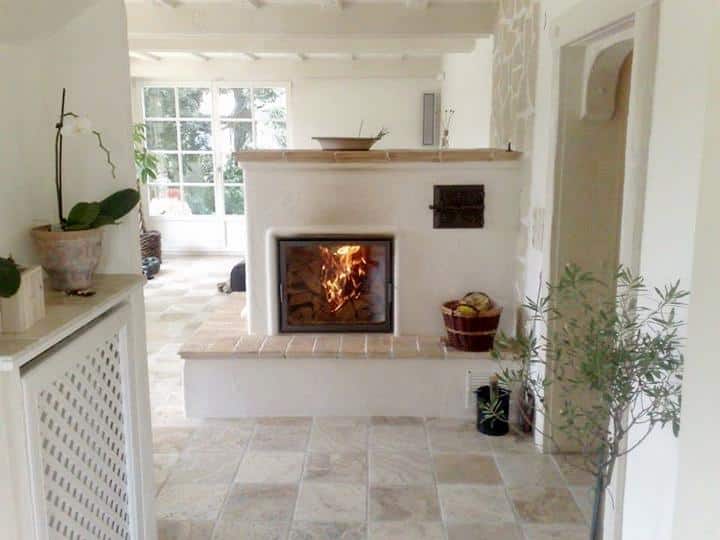 Heller Speicherofen in mediterranem Landhausstil mit sichtbarem Holzfeuer