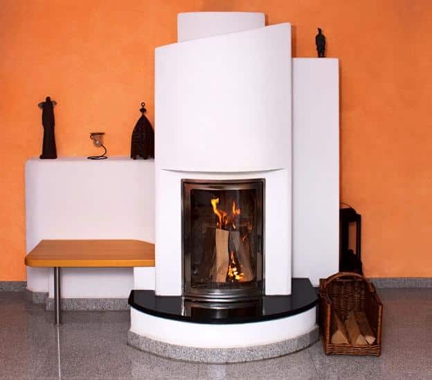 Moderner Speicherofen mit asymmetrischer Front und Holzfeuer vor orangefarbener Wand