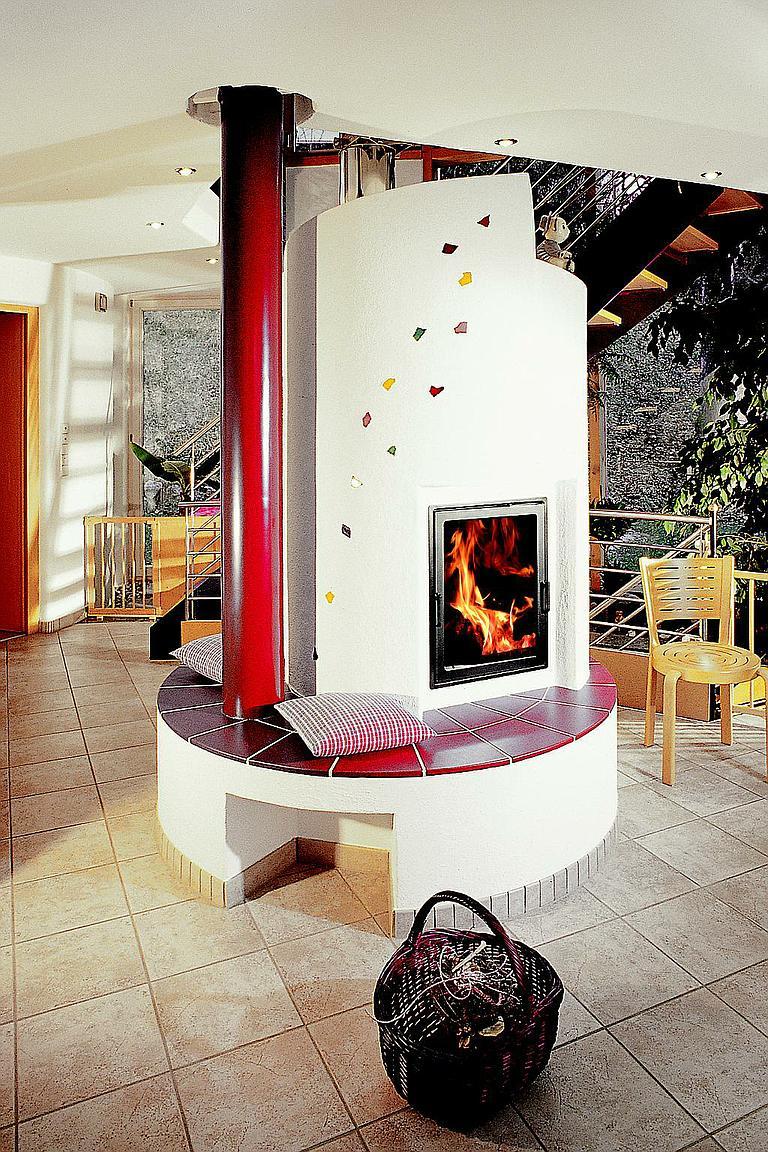 Kamin im traditionellen Design mit rotem Schornstein und eingebauter Sitzbank, flammendes Feuer sichtbar.