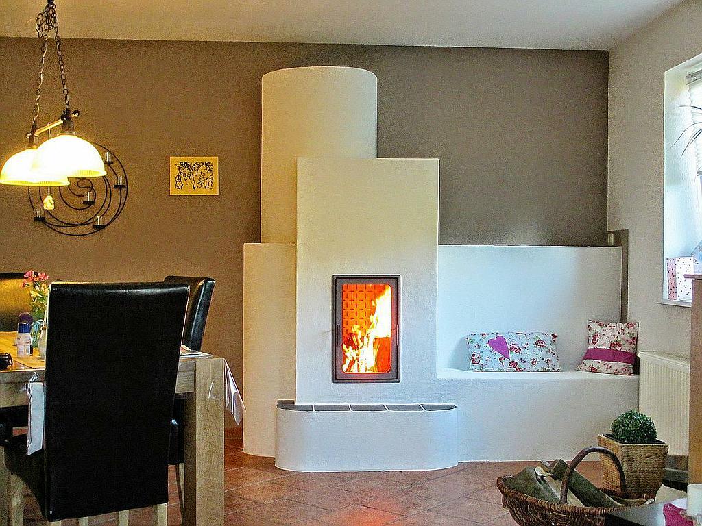 Kamin in weißem Design mit Sitzbank im Esszimmer, mit blumigen Kissen.