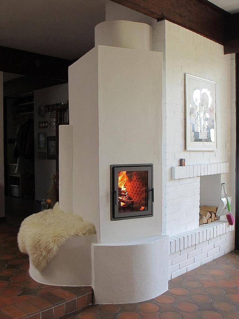 Moderner Speicherofen in weißem Design mit Kamin und Holzablage.