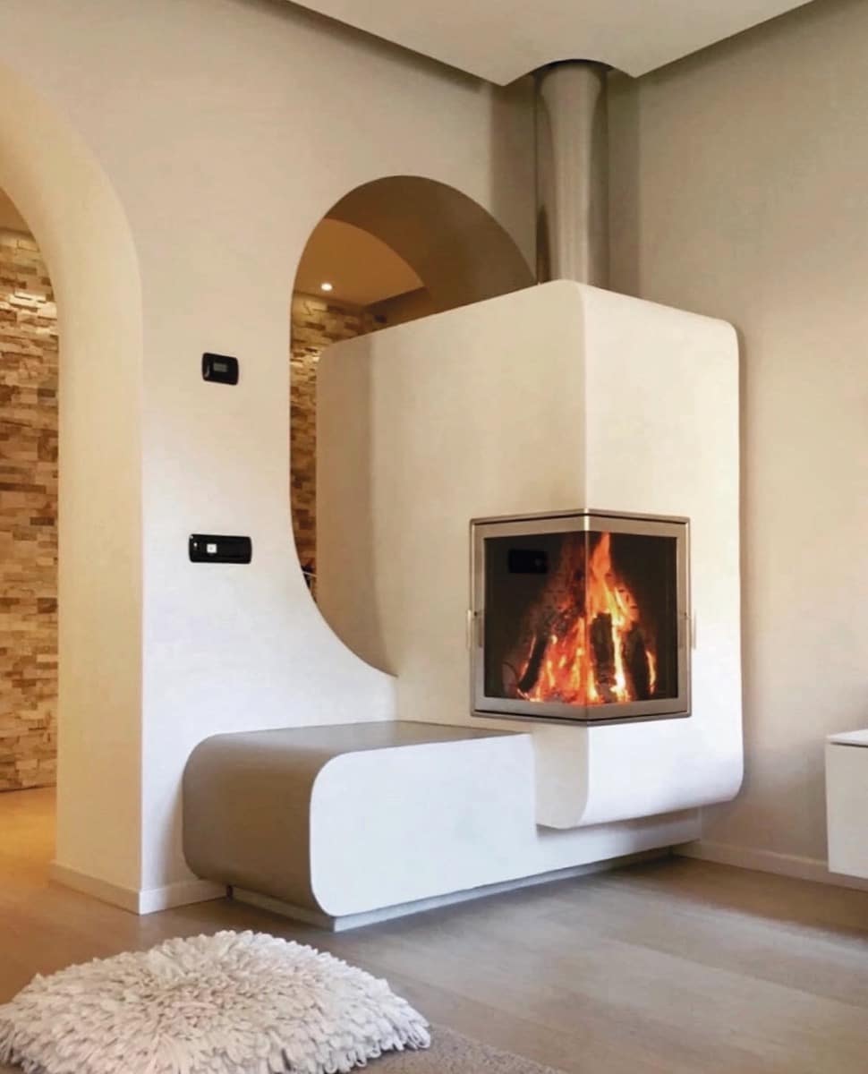 Design-Grundofen mit organischer Form und Sitzbank in hellem Wohnzimmer